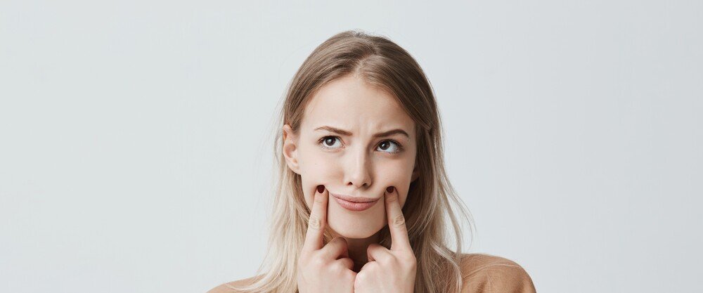 Mo&ccedil;a loira tocando as bochechas pensando como diminuir
